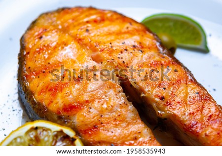 Salmon fish filled grilled for dinner and served on white plate with lemons in seafood restaurant.Download royalty free curated images collection with foods for design template