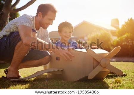 son and dad playing with toy aeroplane in the garden at home having fun together and smiling Royalty-Free Stock Photo #195854006