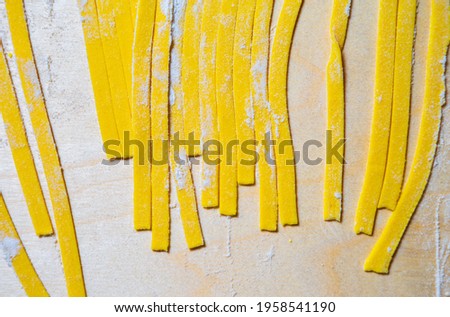 Traditional Italian pasta noodles being prepared from wholegrain wheat flour in restaurant kitchen,shot in flat lay directly from above on wooden table.Download royalty free curated images collection