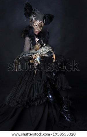 Amazon, woman warrior, mythical creature in black suit, eyes closed and dragon. Photo in the studio. The concept of a fairy tale, legend, theater, cinema