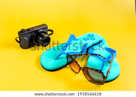 Beach slippers, flip-flops, sunglasses and a camera on the Yellow background. Summer vacation concept. Close-up. High quality photo