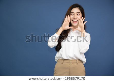 Asian Business woman with open mouths raising hands screaming announcement isolated on blue background