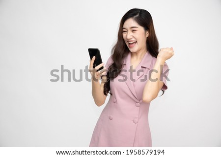 Cheerful Asian businesswoman using smartphone and receiving good news from the message on mobile chat application over white background