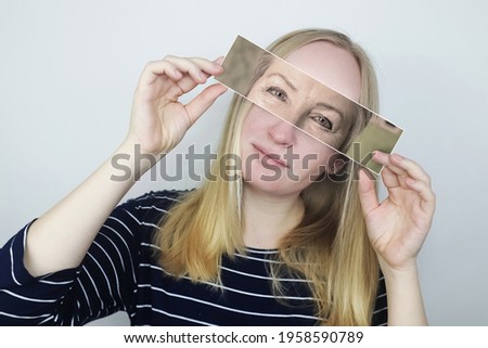 The girl holds a photograph of her old mother to her face. Aging, genetics, family tree and loss of youth concept. Before and after age-related changes. Vintage photographs