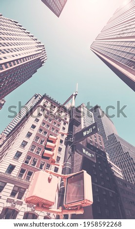 Looking up at Manhattan buildings at Wall Street against the sun, color toning applied, New York City, USA.