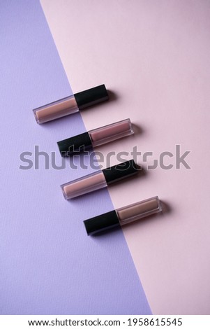 four lipsticks are arranged in a row on a pink and purple background