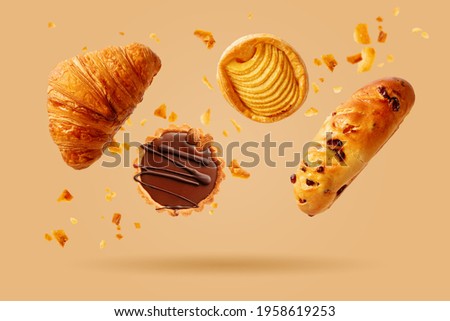 Freshly baked croissant and sweet pastries flying in air. Sweet dessert. Baked goods.  Royalty-Free Stock Photo #1958619253