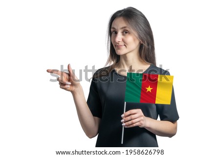 Happy young white woman holding flag Cameroon and points to the left isolated on a white background.