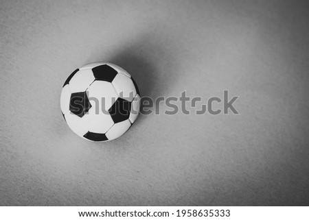 Football game concept, a soccer ball with classic black and white pentagons photographed from above on a background with texture, ample space available for text. Royalty-Free Stock Photo #1958635333