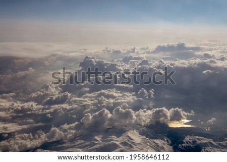 View from a great height through the clouds to the mountains and the earth, the movement of air masses. Concept: God's view of the earth, the view from the plane window.