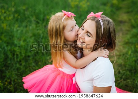 Portrait of a daughter hugging mother on nature on summer day vacation. Mom and girl walk in the park. Happy young family spending time together. Concept of friendly family. Close Up.