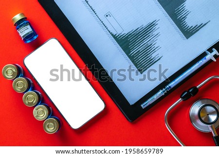 Medical application. Hospital equipment: doctor stethoscope, healthcare charts, syringe with needle and black smartphone with blank screen on red background.. Mockup generic device