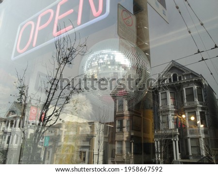 san francisco painted ladies reflected on shop window with neon open sign and disco ball