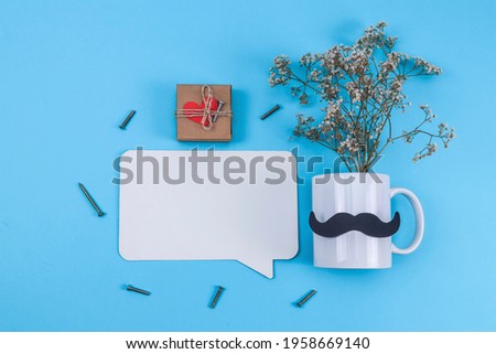 A mug with dried flowers, a gift, nails and a callout lie on a blue background with a place for text, a close-up top view.