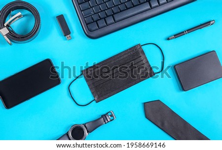 Modern business set of male accessories with a medical mask lie on a light blue background, close-up top view.
