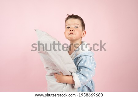 Cute funny boy with big pillow on pink background. Child sleep concept. High quality photo