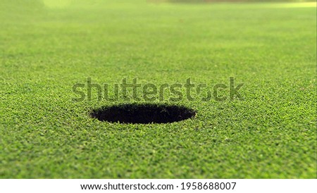 A hole on the golf course in close up view with green grass ground background. Royalty-Free Stock Photo #1958688007
