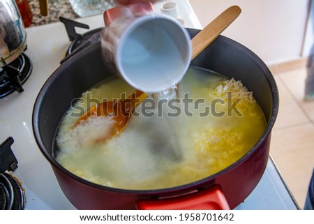 Adding boiled water to roasted rice in a pot