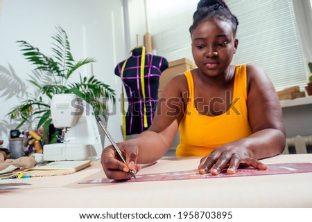 afro woman drawing pattern plotting paper in workshop