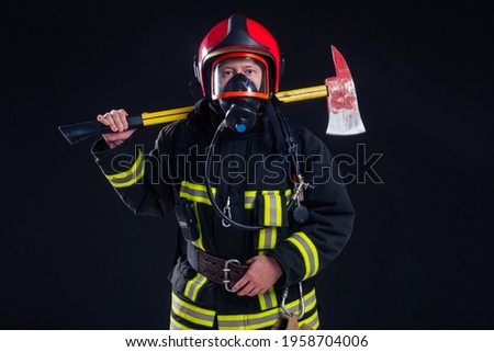 portrait strong fireman in fireproof uniform holding an ax in his hands black background studio