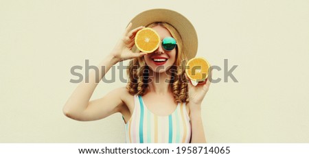 Summer positive portrait of cheerful smiling young woman covering her eyes with slices of orange wearing a straw hat on a white background Royalty-Free Stock Photo #1958714065