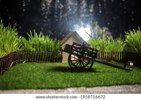 Full moon over quiet village at night. Decorative toy carriage at house with giant green grass under the moonlight. Selective focus