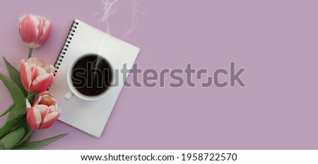 cup of coffee notebook flower tulip on colored background