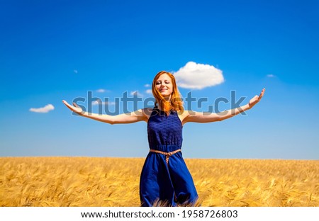 Redhead girl at wheat field in summer day.