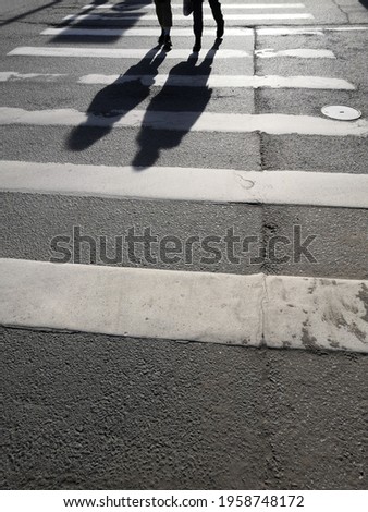 Asphalt texture background with legs and shadows citizens crossing road on pedestrian zebra