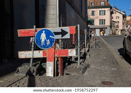 Road construction with warning sign and barriers on an urban pavement