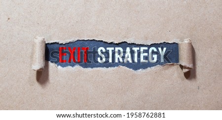 Exit Strategy text with a person holding a pen on a wooden desk.
