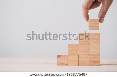 Hand putting and stacking blank wooden cubes on table with copy space for input wording and infographic icon.