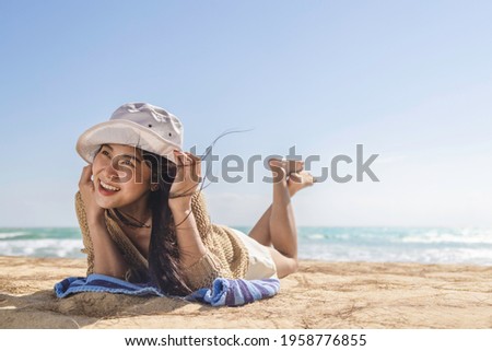 Summer vacations concept, Asian tourist long hair young woman in hat happy smiling laughing lying down on the beach