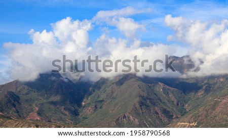 An aerial shot of rocky mountains under blue cloudy sky