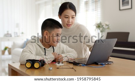 Young asia student remotely learn online at home with parent in coding robot car and electronic board cable in STEM, STEAM, mathematics engineer science technology computer code in robotics for kids. Royalty-Free Stock Photo #1958795845