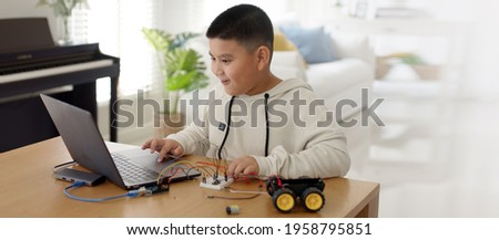 Young asia student remotely learn online at home in coding robot car and electronic board cable in STEM, STEAM, mathematics engineering science technology computer code in robotics for kids concept. Royalty-Free Stock Photo #1958795851
