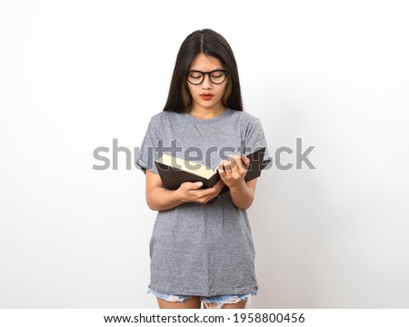 Portrait of attractive asian student woman standing and holding reading a book in white room.