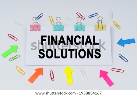 Business and finance concept. On the table there are paper clips and directional arrows, a sign that says - FINANCIAL SOLUTIONS
