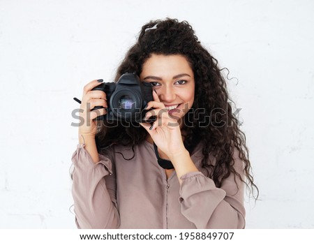 Portrait of Afican woman holding digital photocamera and laughing over white background in studio.