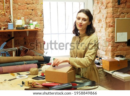 brunette woman folds packing box in sewing workshop