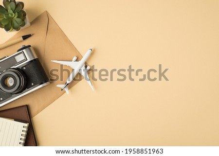 Top view photo of plant pen planners camera and plane model on craft paper envelope on isolated beige background with copyspace