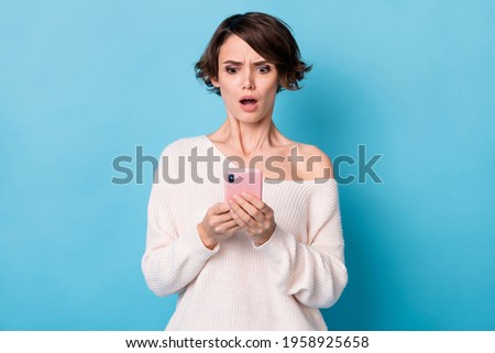 Photo portrait of upset girl holding phone in two hands isolated on pastel blue colored background