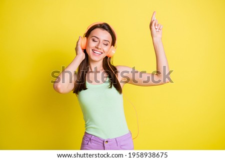 Photo of carefree lady dance raise finger closed eyes wear headphones green top isolated yellow color background