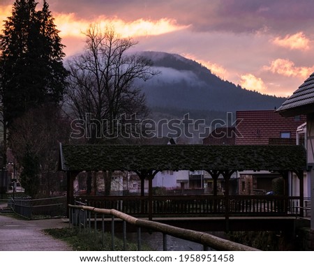 Beautiful view on the sunset in a small town in the Germany. Big mountains on the background. Fog and clouds hiding peak of the mountain. Schwarzwald nature