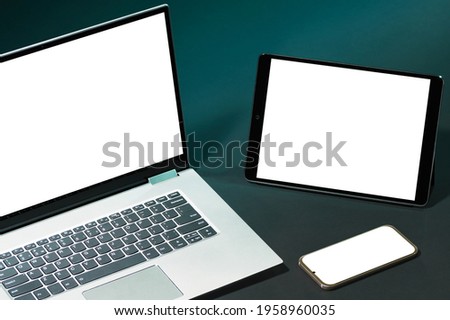 Set with smartphone, digital tablet and laptop with white screens for your design on green background.