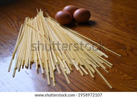 Fresh egg pasta. spaghetti on wooden board and chicken eggs. ingredients for cooking spaghetti.