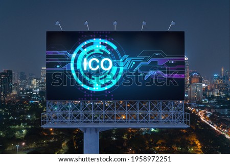 ICO hologram icon on billboard over panorama city view of Bangkok at night time. The hub of blockchain projects in Southeast Asia. The concept of initial coin offering, decentralized finance
