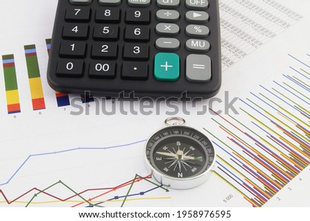 Right direction in financial world concept, calculator and compass on financial reports.