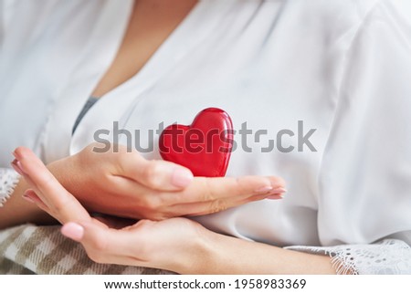 Adult woman in mask showing heart shape at home Covid-19 concept