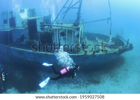 Scuba Divers Exploring underwater ship wreck. Diver discovering the shipwreck sunken at deep sea bottom Royalty-Free Stock Photo #1959027508